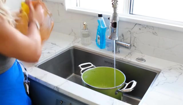 A pot and cutting board being washed at a kitchen sink